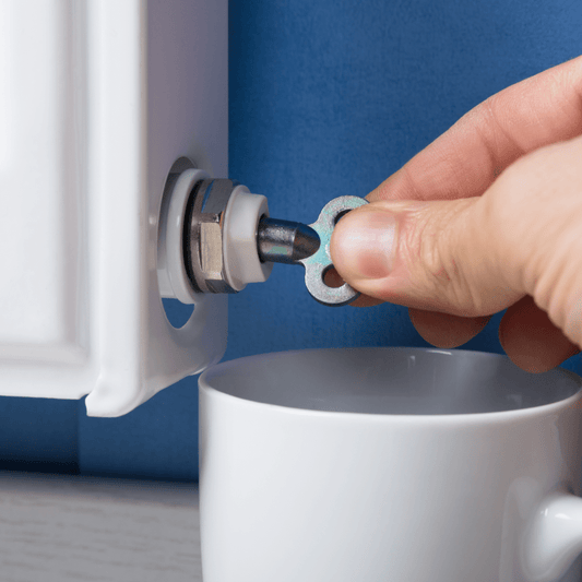 Hand ontlucht een radiator met een ontluchtingssleutel