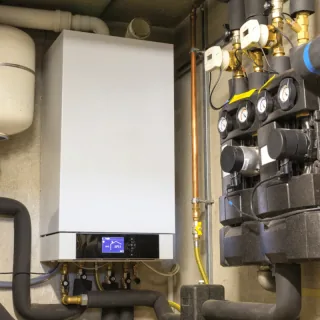 Cv-ketel met leidingwerk en verdeler in een meterkast